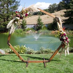 Septigon wedding arch, rentable as an add on at Mountian House Estate.  This is the perfect frame for couples getting married with a pond backdrop. These gorgeous flowers with bugundy, pampas grass, and succulents were arranged by Succulents for Hire. Photo credit: Josh Isaacs Photography